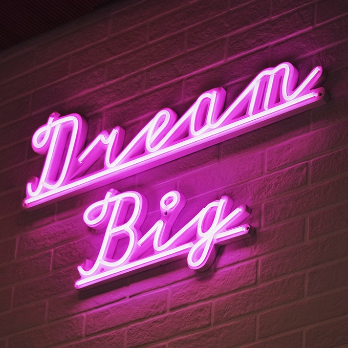 Neon sign in a script style spelling out the words "Dream Big".